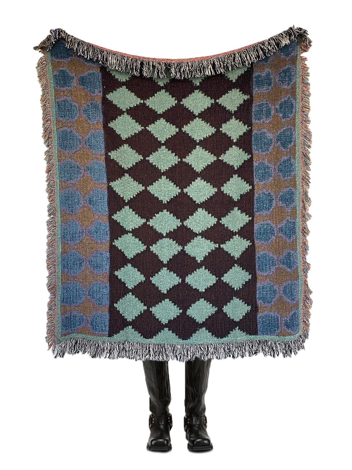 A woven throw blanket with a diamond and medallion-inspired pattern in a combination of blue, green, and brown colors, displayed by a model.